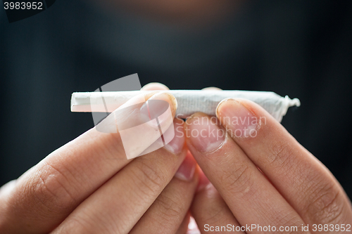 Image of close up of addict hands with marijuana joint