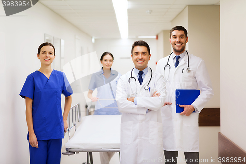 Image of group of happy doctors with gurney at hospital