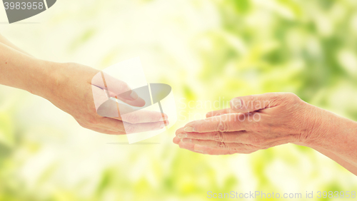 Image of close up of senior and young woman hands