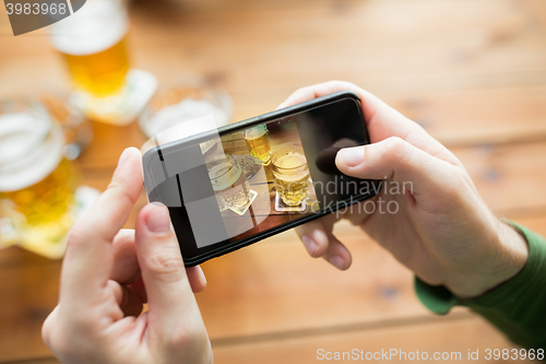 Image of close up of hands with smartphone picturing beer