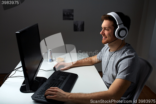 Image of man in headset playing computer video game at home