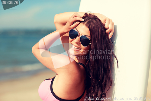 Image of smiling young woman with surfboard on beach