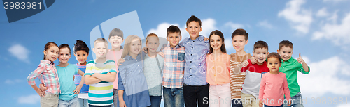 Image of group of happy children hugging over blue sky