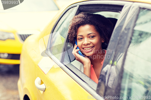 Image of happy african woman calling on smartphone in taxi