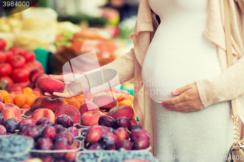 Image of pregnant woman choosing fruits at street market