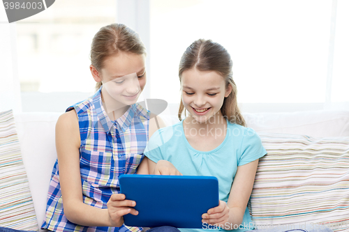 Image of happy girls with tablet pc sitting on sofa at home