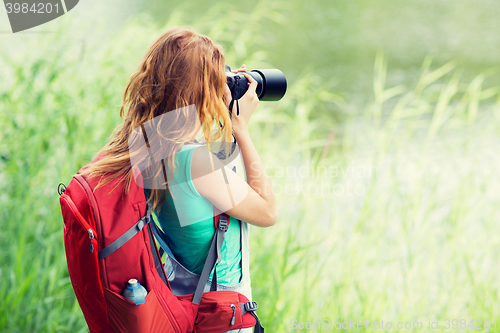 Image of young woman with backpack and camera outdoors