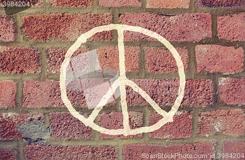 Image of peace sign drawing on red brick wall