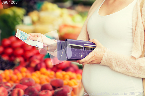 Image of pregnant woman with wallet buying food at market