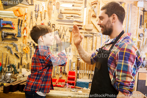 Image of father and little son making high five at workshop