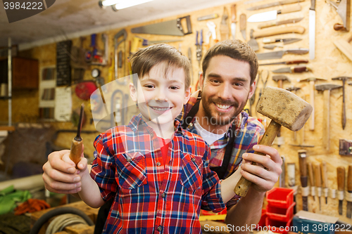 Image of boy with dad holding chisel and hammer at workshop