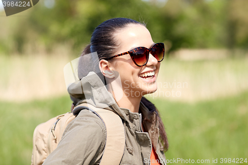 Image of happy young woman with backpack hiking outdoors