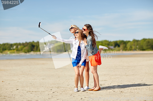 Image of group of smiling women taking selfie on beach