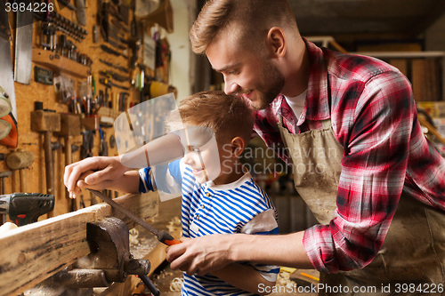 Image of father and son with rasp working at workshop