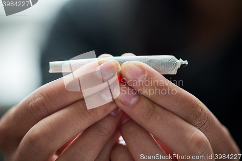 Image of close up of addict hands with marijuana joint