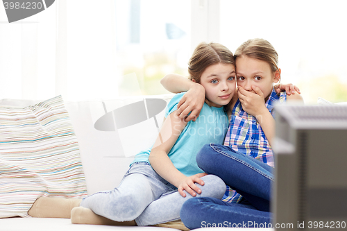 Image of scared little girls watching horror on tv at home