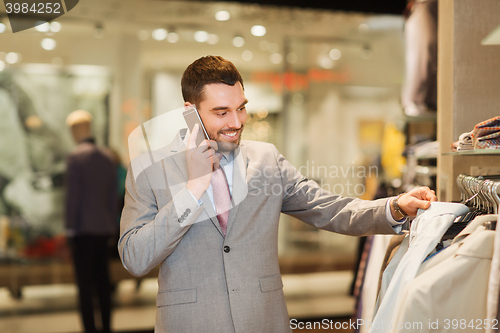 Image of happy man calling on smartphone at clothing store