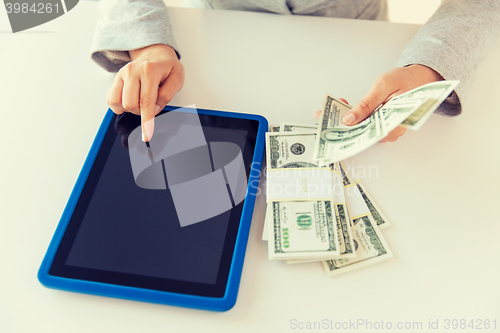 Image of close up of woman hands with tablet pc and money