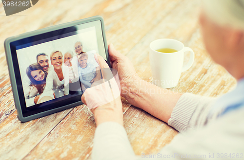 Image of senior woman with family photo on tablet pc screen