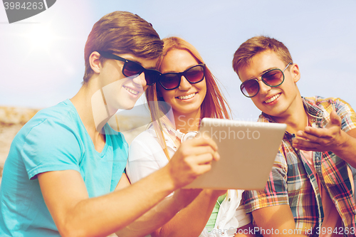 Image of group of smiling friends with tablet pc outdoors