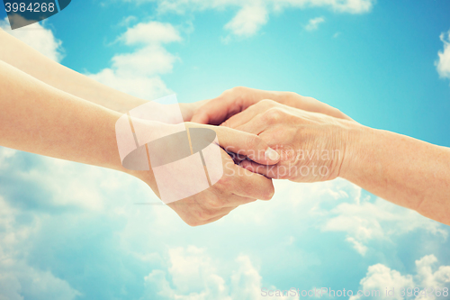 Image of close up of senior and young woman holding hands