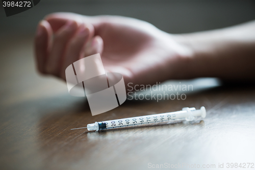 Image of close up of addict hand and used drug syringe