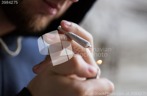 Image of close up of addict lighting up marijuana joint