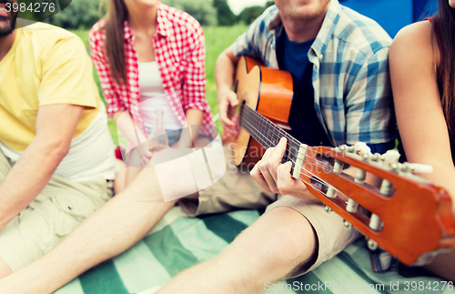 Image of happy friends with drinks and guitar at camping