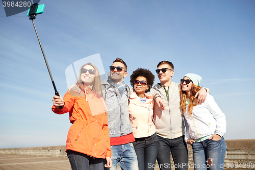 Image of smiling friends taking selfie with smartphone