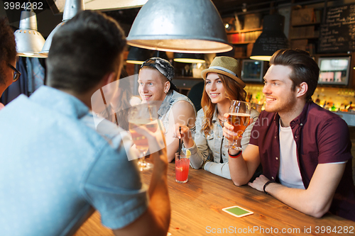 Image of happy friends with drinks talking at bar or pub