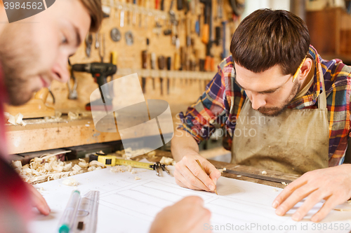 Image of carpenters with ruler and blueprint at workshop