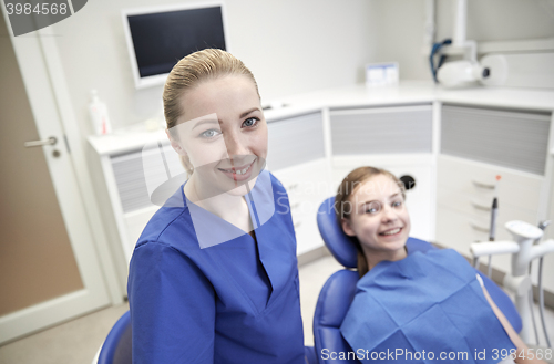 Image of happy female dentist with patient girl at clinic