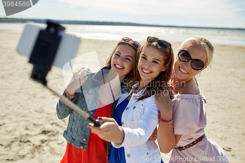 Image of group of smiling women taking selfie on beach