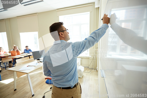 Image of students and teacher writing on school white board