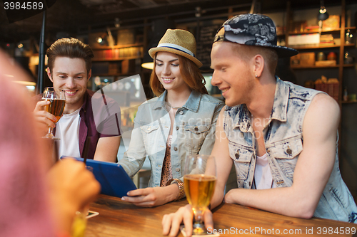 Image of happy friends with tablet pc and drinks at bar