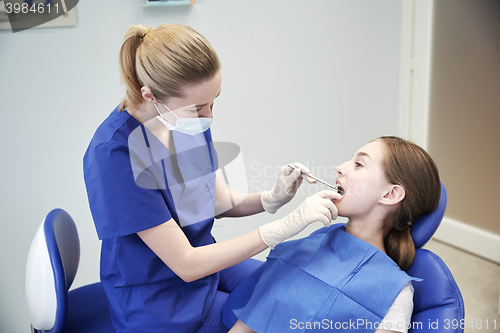 Image of female dentist checking patient girl teeth