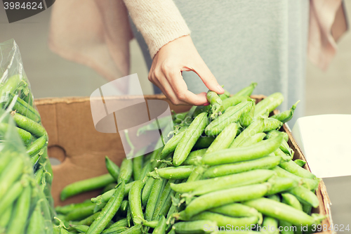 Image of woman hand choosing green peas at street market