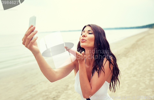 Image of young woman taking selfie with smartphone