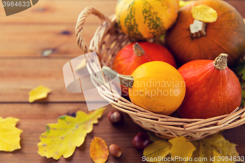 Image of close up of pumpkins in basket on wooden table