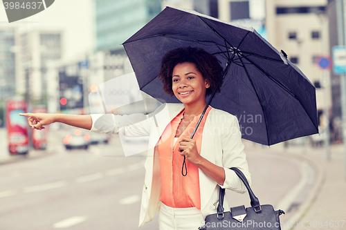 Image of happy african woman with umbrella catching taxi