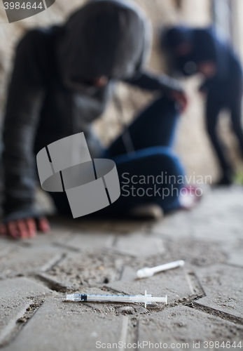 Image of close up of addicts and drug syringes on ground