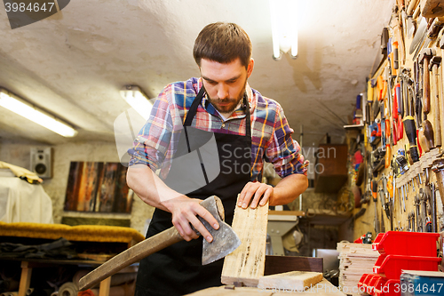 Image of carpenter with ax and board working at workshop