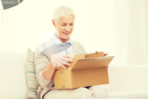 Image of happy senior woman with parcel box at home