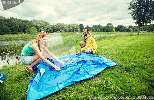 Image of happy couple setting up tent outdoors