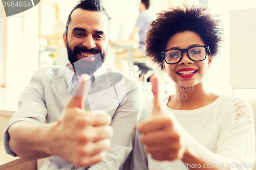 Image of happy creative team in office showing thumbs up