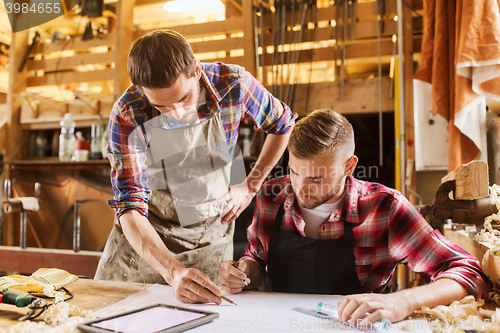 Image of workmen with tablet pc and blueprint at workshop