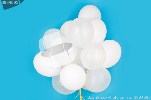 Image of close up of white helium balloons over blue