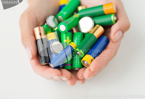 Image of close up of hands holding alkaline batteries heap