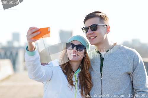 Image of smiling couple with smartphone taking selfie