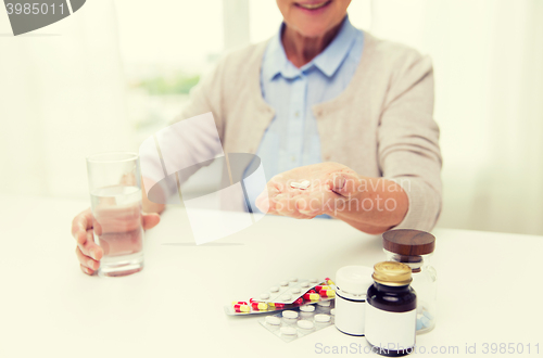 Image of happy senior woman with water and pills at home